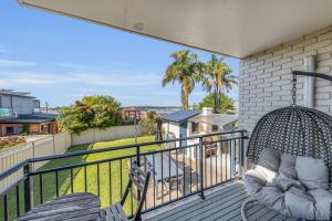a porch with a swing and two chairs on a balcony at Capri Apartments in Merimbula