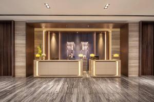 a lobby with two reception desks and a man in the mirror at Courtyard by Marriott Shanghai International Tourism and Resorts Zone in Shanghai