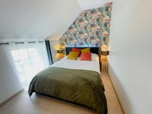 a bedroom with a bed with colorful pillows on it at Gîte à Luzillé avec jardin privé et climatisation - FR-1-381-532 in Luzillé