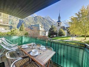 einen Holztisch und Stühle auf einem Balkon mit einer Kirche in der Unterkunft Appartement Chamonix-Mont-Blanc, 4 pièces, 6 personnes - FR-1-507-74 in Chamonix-Mont-Blanc