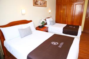 Habitación de hotel con 2 camas con sábanas blancas en Hoteles Riviera Cayma, en Arequipa