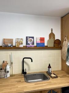 a kitchen counter with a sink and a shelf with books at Tiny house 15min away from Opera Garnier in Argenteuil +11 photos