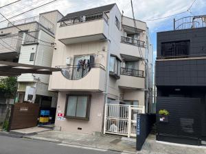 東京的住宿－Cozy inn Oyama，大街上高大的白色建筑,设有阳台