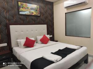 a bedroom with a large white bed with red pillows at Royal Neptunian Beach Cottages Arambol Goa in Arambol