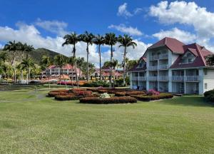 un complexe avec des palmiers et une grande cour dans l'établissement TI OASIS vue Mer dans village Pierre & Vacances, à Sainte-Luce