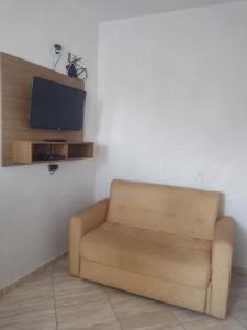 a living room with a chair and a television at Apartamento avenida 06 com ar condicionado in São Thomé das Letras