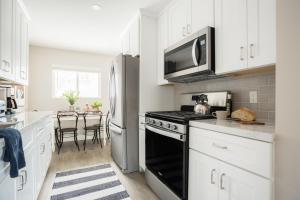 a kitchen with white cabinets and a black stove top oven at Seashore VII by AvantStay Modern La Jolla Flat 5mins from the Beach in San Diego