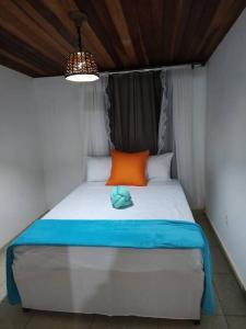 - un lit avec un oreiller orange et bleu dans l'établissement Casa de Campo: Sítio Santa Helena-Mendes RJ, à Mendes