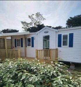 a white house with blue windows and a fence at Mobilhome 6 couchages in Vic-la-Gardiole