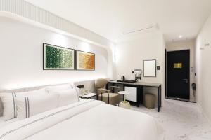 a white bedroom with a bed and a desk at Mari Hotel in Chungju