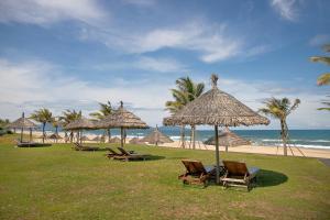 a group of chairs and umbrellas on the beach at Ocean Villa Pool Retreat In Da Nang in Danang