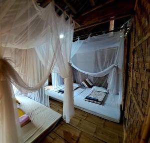 two beds in a room with white mosquito nets at Muong Bi Homestay - Uncle Lon - Luy Ai village in Hòa Bình