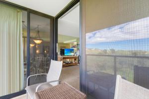 a balcony with white chairs and a view of a room at Kihei Surfside 613 - MCH in Kihei