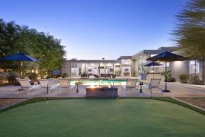 a patio with chairs and a fire pit and a building at Polo Villa 10 by AvantStay Backyard Oasis w Putting Green 260-320 6 Bedrooms in La Quinta