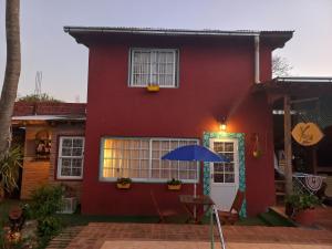 ein rotes Haus mit einem blauen Regenschirm davor in der Unterkunft Mary's House in Puerto Iguazú