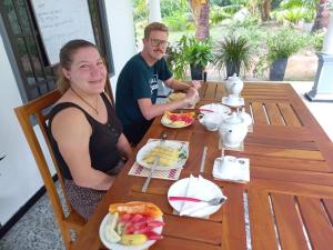 mężczyzna i kobieta siedzący przy stole z jedzeniem w obiekcie Hanguk Lanka Lagoon Villa w Tangalli