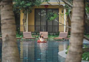 kobieta siedząca na tratwie w basenie z wodą w obiekcie Ahoy Hoi An Boutique Resort & Spa w Hoi An