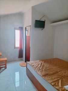 a bedroom with a bed and a flat screen tv at Mozza guest house in Klaten