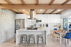 a kitchen with white cabinets and a table with chairs at Mission Point 2 by AvantStay Mission Beach Home w Large Balcony Steps to Beach in San Diego