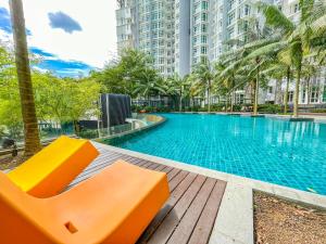 una piscina con un banco naranja frente a un edificio en 1Medini Theme Suite by Nest Home【LEGOLAND】 en Nusajaya