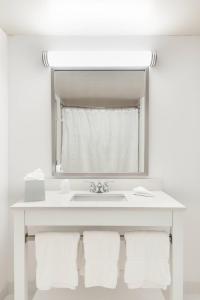 Four Points by Sheraton Columbus-Polaris في كولومبوس: حمام أبيض مع حوض ومرآة