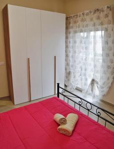1 dormitorio con 1 cama roja y 2 toallas en Residence daniele ATTICO VISTA MARE, en Borgo Sabotino