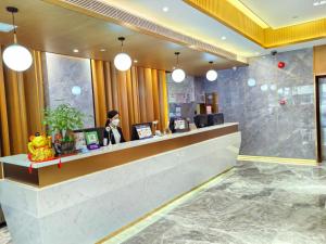 una mujer parada en un mostrador en el vestíbulo del hotel en Slowcom┃Yuebei Hotel （Guangzhou Provincial Government), en Guangzhou