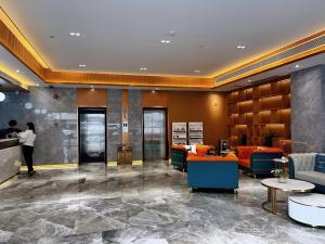 a lobby with orange and blue furniture and a woman at Slowcom┃Yuebei Hotel （Guangzhou Provincial Government) in Guangzhou