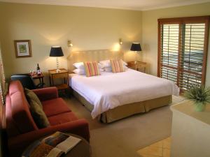 a bedroom with a large white bed and a couch at The Beach House At Bayside in Albany