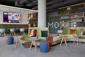 a room with a couch and tables and a tv at Moxy Vienna City East in Vienna