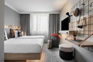 a hotel room with two beds and a tv at Moxy Vienna City East in Vienna