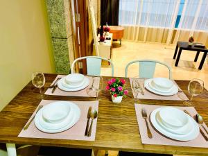 a wooden table with white plates and silverware on it at vortex suites klcc HOLIDAY apartment in Kuala Lumpur