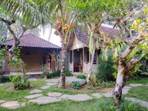 a house with palm trees in front of it at Tangkas wooden house in Tampaksiring