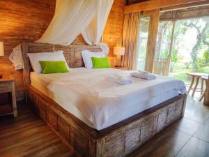 a bedroom with a large bed with green pillows at Tangkas wooden house in Tampaksiring +10 photos