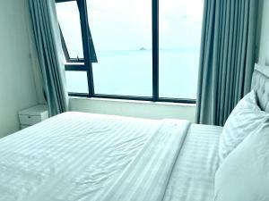 a white bed in a room with a window at Mường Thanh Oceanus Apartment in Nha Trang