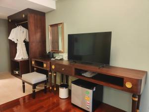 a living room with a television and a desk with a chair at Siri Grand Bangkok Hotel in Bangkok