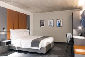 a bedroom with a white bed and a desk and a chair at The Londoner Hotel St. Julian's in St. Julianʼs