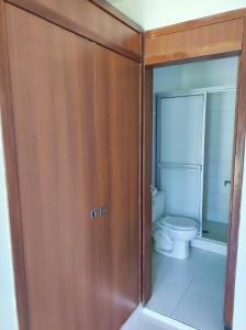 a bathroom with a toilet and a wooden cabinet at Hospedaje villa luz in Pitalito