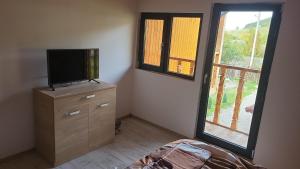 a bedroom with a tv on a dresser and a window at CABANA ADAM SI EVA in Gura Râului