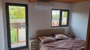 a bedroom with a bed and two windows at CABANA ADAM SI EVA in Gura Râului