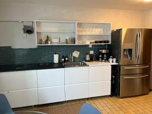 a kitchen with white cabinets and a stainless steel refrigerator at Storahuset Helsingborg in Helsingborg