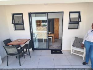 uma pessoa de pé num quarto com uma mesa e cadeiras em Karoo Retreat- Self Catering Villas and Bed & Breakfast em Oudtshoorn