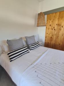 ein weißes Bett mit schwarzen und weißen Kissen darauf in der Unterkunft Karoo Retreat- Self Catering Villas and Bed & Breakfast in Oudtshoorn
