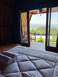 a bed in a room with a view of a patio at D’Taman cabin Kintamani in Kubupenlokan