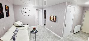 Una sala de estar con un sofá y un reloj en la pared. en Two-Bedroom Apartment in Kutaisi Nest 1, New Linen, Free Parking, en Kutaisi