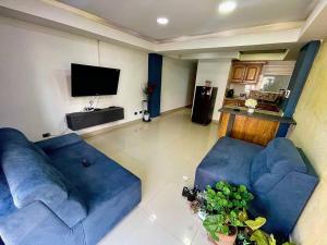 sala de estar con 2 sofás azules y TV de pantalla plana en Apartamento Laureles-estadio Luxury en Medellín