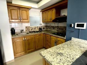 cocina con armarios de madera y encimera de granito en Apartamento Laureles-estadio Luxury en Medellín