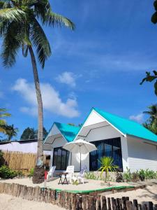 a white building with a blue roof and a palm tree at Mook tawan Beach house in Ko Mook