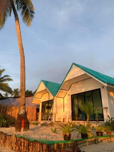 ein Haus mit einem grünen Dach und einer Palme in der Unterkunft Mook tawan Beach house in Ko Mook