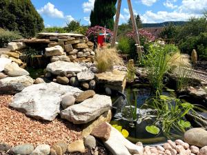 a garden with a pond and rocks and plants at Roulotte de Charme 